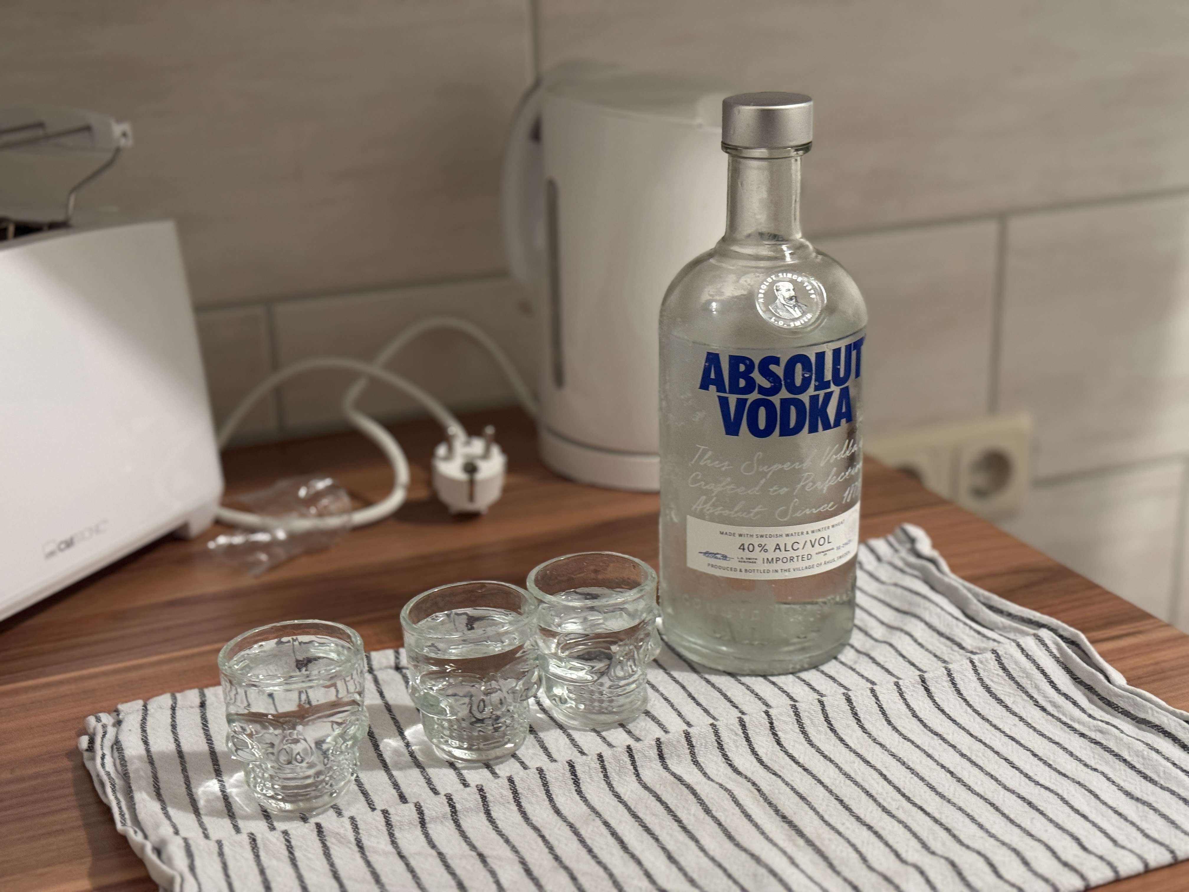 Vodkaflasche und kleine Gläser auf einem Tisch.
